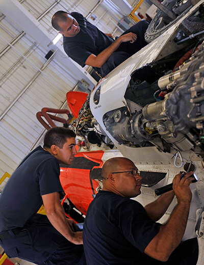 U.S. Coast Guard Aviation Maintenance Technician 1st Class Joesoph Villa, bottom right, and Aviation Maintenance Technician 3rd Class Jacob Ylitalo, bottom left, work on an MH-60 Jayhawk helicopter 130801-G-XO423-003